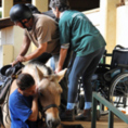 רכיבה טיפולית מכללת עוזרים לנכה לעלות על סוס
