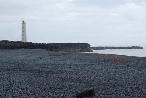 מגדלור על חוף חלוקי בזלת שחורים