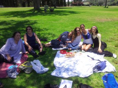 a group of women sitting on a blanket on the grass